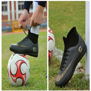 Close-up of black high-top soccer shoes with gold graphics on grass field