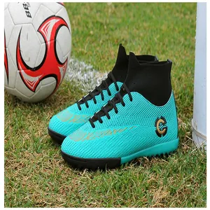 Close-up of turquoise high-top soccer shoes on a green grass field with a soccer ball