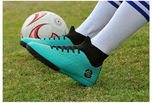 Detailed view of turquoise high-top soccer shoes with turf studs on green grass