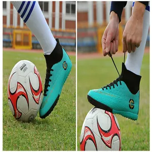 Detail view of turquoise high-top soccer shoes on a green field with a soccer ball