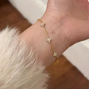 Elegant gold bracelet with sparkling zircon flower motifs on a wrist.