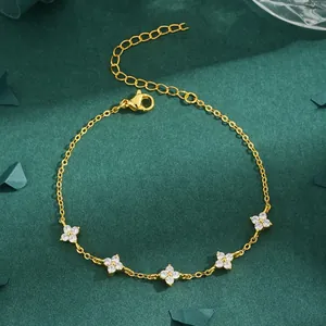 Macro view of gold bracelet featuring elegant white zircon four-leaf clover charms