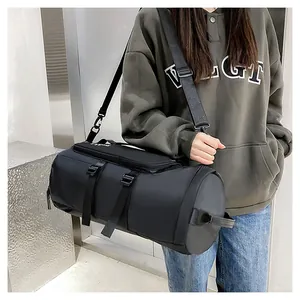 Close-up of a versatile black cylindrical sports gym bag carried by a female model.