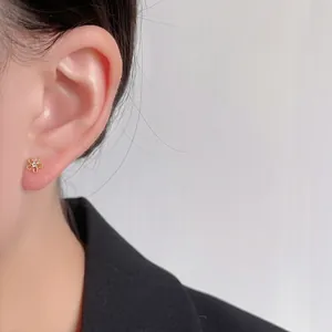 Detaillierte Nahaufnahme von Mini-Zirkon-Blumensteckern am Ohr, mit 14K Goldbeschichtung