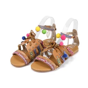 Detail view of Bohemian platform sandals with colorful pom-poms and leaf charm