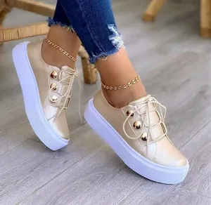 Κοντινή λεπτομέρεια από γυναικεία χρυσά sneakers με πλατφόρμα και μεταλλικά τρουκς