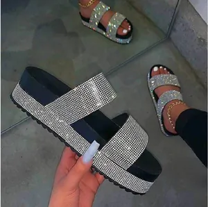 Close-up of black platform sandals with shimmering rhinestone straps in a lifestyle view.