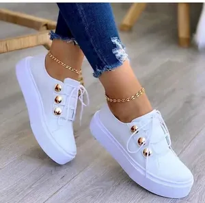 Λεπτομερής προβολή λευκών sneakers με πλατφόρμα, διακοσμητικά χρυσά κουμπιά και σόλα