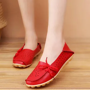 Detail of red perforated women's flat shoes with decorative bow on wooden background