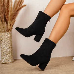 Détail rapproché de bottines noires à talons épais en suédine avec un design à bout pointu.