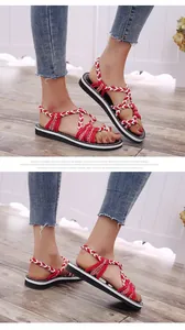 Detalle del patrón de cuerda trenzada roja y blanca de estas sandalias playeras planas.