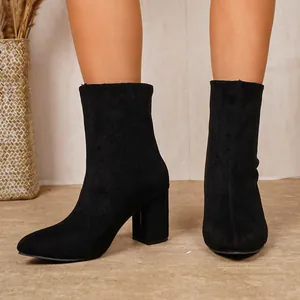 Gros plan de bottines en daim noir à talons blocs pour femmes dans un décor intérieur