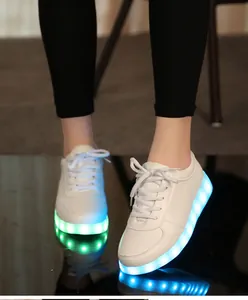 Détail des baskets à LED blanches avec semelles bleues et vertes lumineuses pour la nuit.