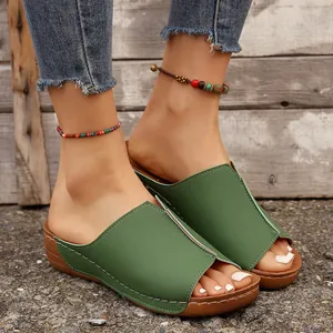 Dettaglio di sandali con zeppa verde da donna con cuciture bianche eleganti e punta aperta