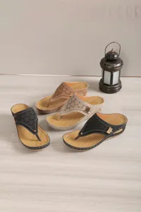 Detail of women's wedge thong sandals with laser-cut patterns and metal buckle accents.