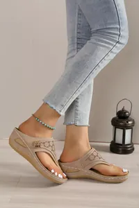 Detail shot of beige platform thong sandals with intricate hollow-out floral patterns