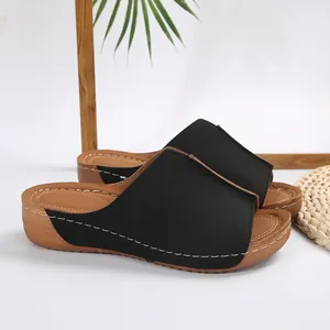 Vista dettagliata di ciabatte con zeppa nere eleganti con cuciture bianche decorative