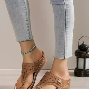 Detail view of brown thong sandals with laser-cut floral patterns and platform wedge.