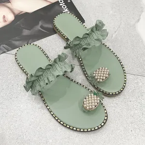 Green ruffle strap flat sandals featuring a pearl-studded pineapple toe loop detail.