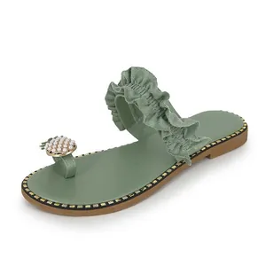 Detail view of green flat toe-ring sandal with ruffle strap and pearl pineapple decor