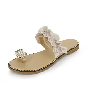 Detailed view of beige toe-ring sandal with ruffled strap and pearl pineapple decor.
