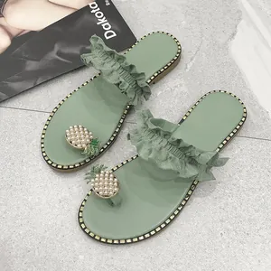 Detailed view of green flat sandals with pearl pineapple and ruffled straps.