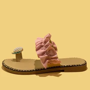 Detailed view of women's flat toe-loop sandals featuring a pearl pineapple accent.