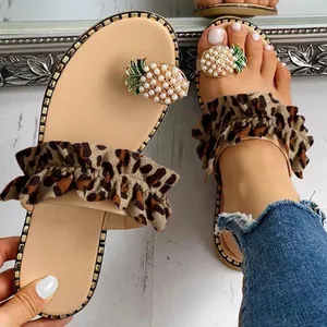 Close-up of leopard ruffle flat sandals with pearl pineapple toe ring detail.