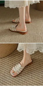 Détail des sandales plates romaines à brides tressées blanc cassé sur un tapis