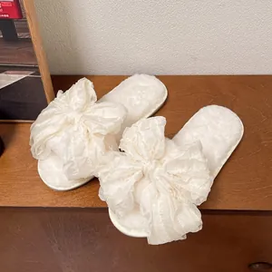 Dettaglio delle eleganti pantofole bianche in peluche con un grande fiocco decorativo in organza