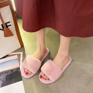 Close-up of pink faux fur slippers worn with a stylish autumn outfit