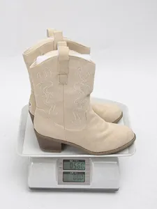 Beige suede embroidered mid-calf boots on a digital scale weighing exactly 0.560 kg.