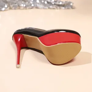 Close-up van een zwart-rode ultra-hoge plateau stiletto met een getextureerde antislipzool.
