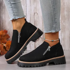 Detailed macro view of black suede women's ankle boots featuring side zipper and lug sole
