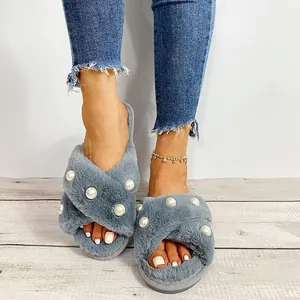 Graue flauschige Cross-Strap-Slipper mit Perlenakzenten auf hellem Holzfußboden