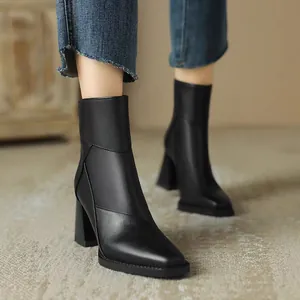 Detailed macro view of black pointed-toe leather boots featuring a stylish chunky heel