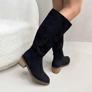 Close-up of elegant black suede knee-high boots with a stylish wooden chunky heel.