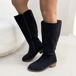 Macro view of black suede knee-high boots featuring block heel and side zipper