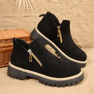 Détail de bottines en daim noir avec une fermeture éclair latérale dorée élégante