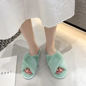 Primer plano de zapatillas de felpa verde claro con tiras cruzadas en suelo de baldosas