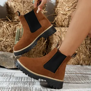 Botines Chelsea de ante marrón para mujer con suelas gruesas en un entorno rústico de paja