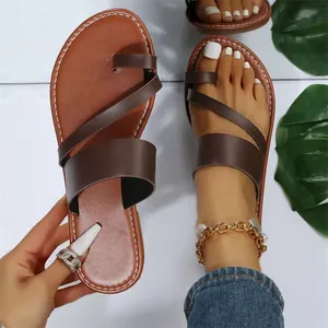 Detail view of stylish brown flat toe-loop sandals for women with asymmetric straps