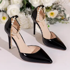Detail of elegant black patent leather high heels with pearl ankle strap and stiletto.