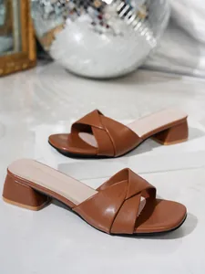 Primer plano de sandalias marrones de tacón grueso con diseño de tiras cruzadas