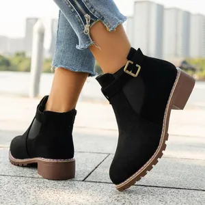 Close-up detail of black suede ankle boots with gold buckle and low square heel
