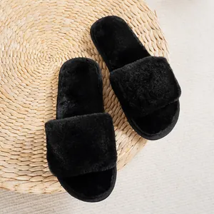 Soft and fluffy black faux fur slides displayed on a natural woven straw background mat