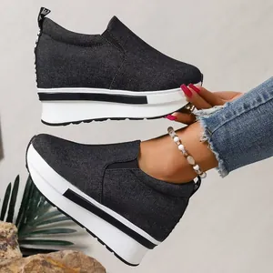 Detalle de zapatillas con cuña de mezclilla negra con suelas de plataforma blancas y negras.