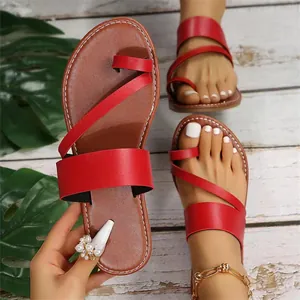 Close-up of red toe-ring flat sandals with brown insoles on wooden background