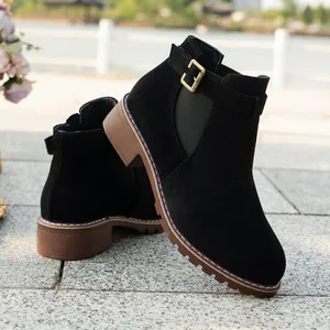 Close-up of black suede ankle boot featuring decorative gold buckle and elastic side