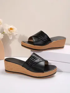 Elegantes sandalias negras con cuña, tira de cocodrilo brillante y suela de grano de madera.